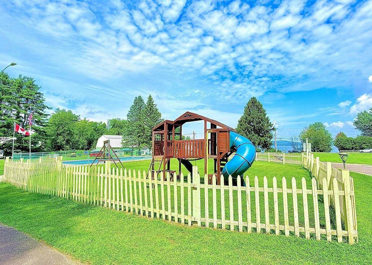 Fenced play area with slide and pool beyond